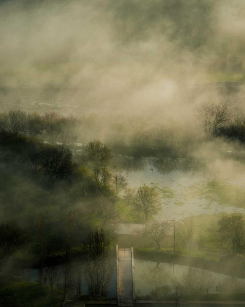 A misty river valley at dawn with a small wooden pier