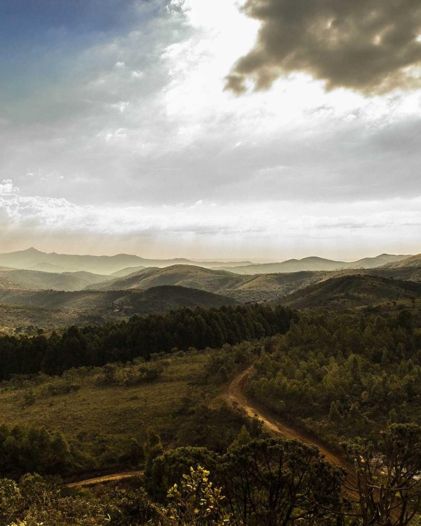 A dirt road winding through green hills at sunset