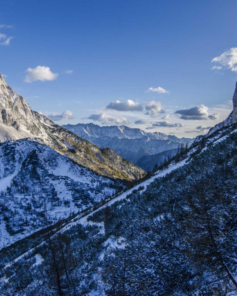 A snow-covered mountain range under a blue sky with scattered clouds