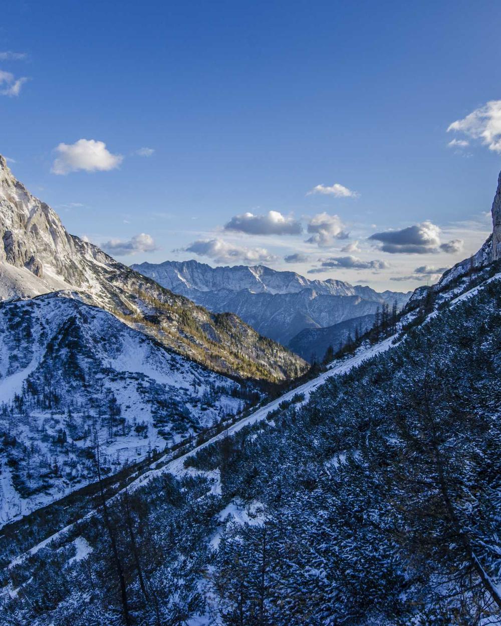 A snow-covered mountain range under a blue sky with scattered clouds